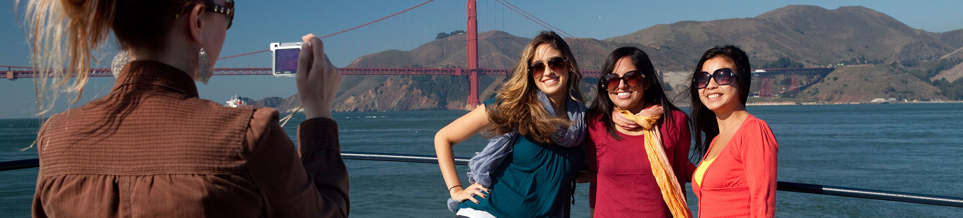 People standing on boat with Golden Gate Bridge in background