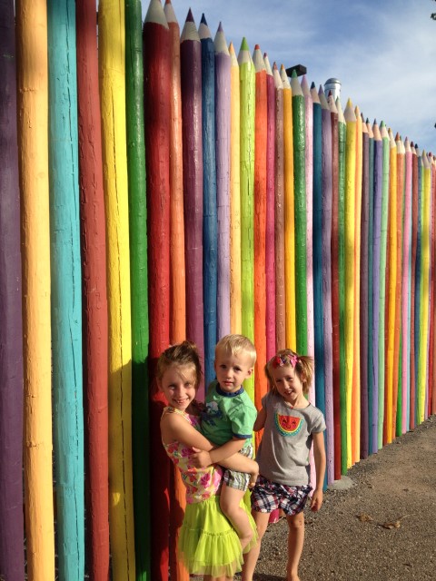 Kids standing in front of a life-sized colored-pencil fence