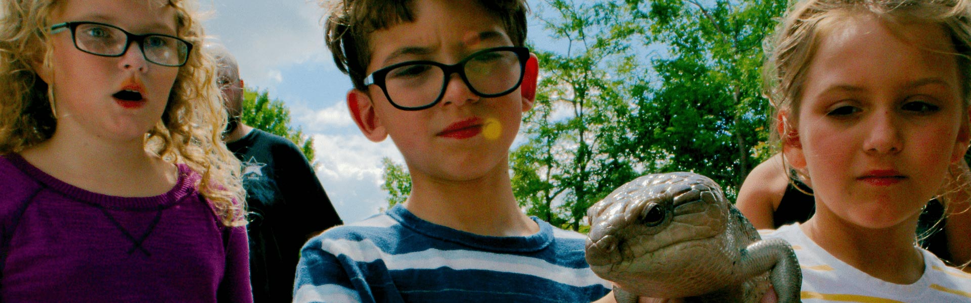 Kids holding and looking at a large lizard