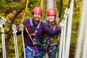 Two people wearing harness for a zipline