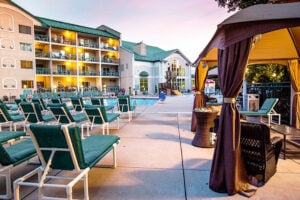 Chairs and a cabana around a pool with hotel in background